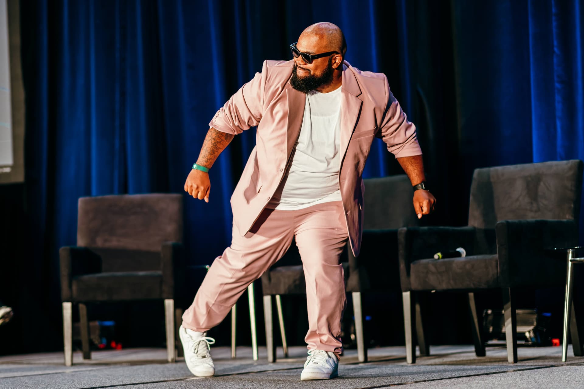 A man in a pink suit is dancing on a stage