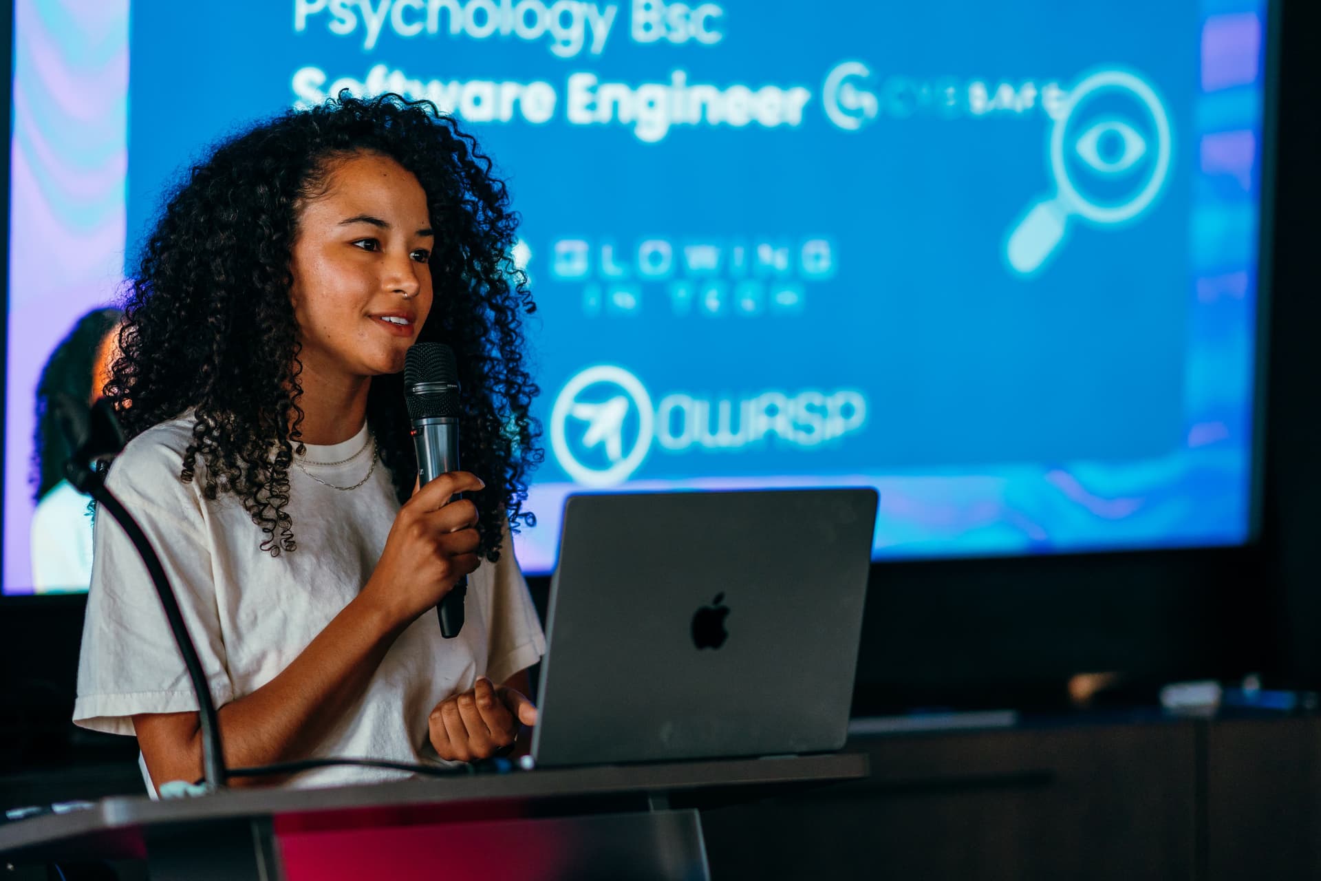 A woman speaking into a microphone in front of a laptop