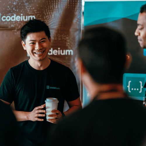 A man holding a cup of coffee standing next to another man